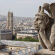 Stone chimera of Notre-Dame de Paris resting its chin in its hand, gazing over the Paris rooftops and the Tour Saint-Jacques