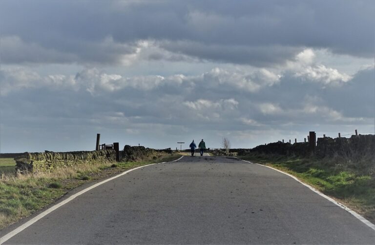 An older couple walking together along a quiet country road.