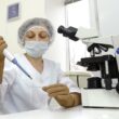 Laboratory technician working at a microscope and pipette in an IVF lab