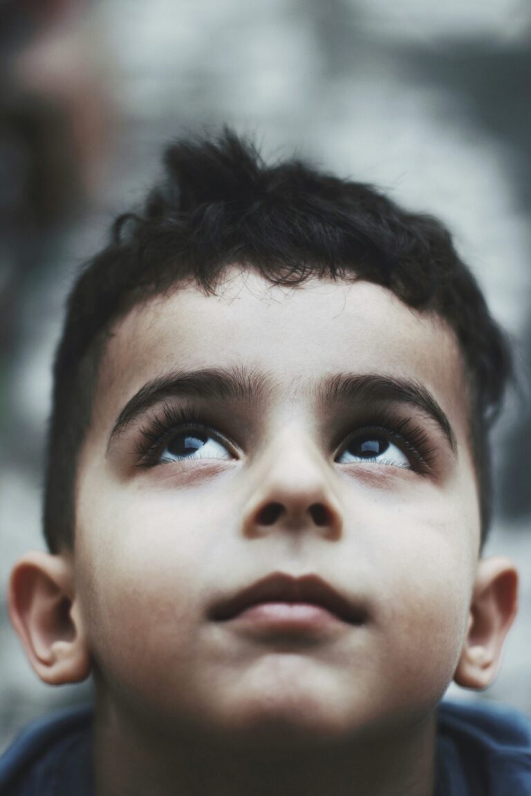 A young boy gazing up toward the sky with a hopeful expression.