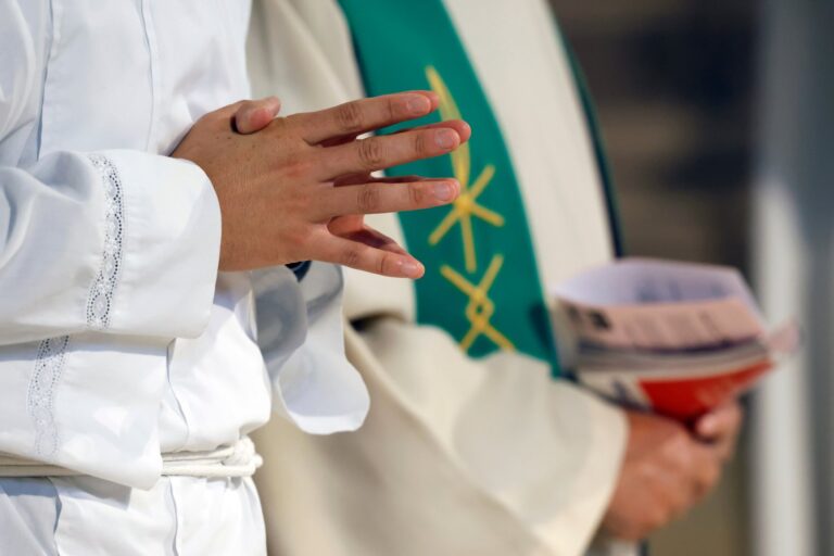 Altar servers kneeling during the Eucharistic celebration at Mass in Saint Agatha Church, Rumilly, France